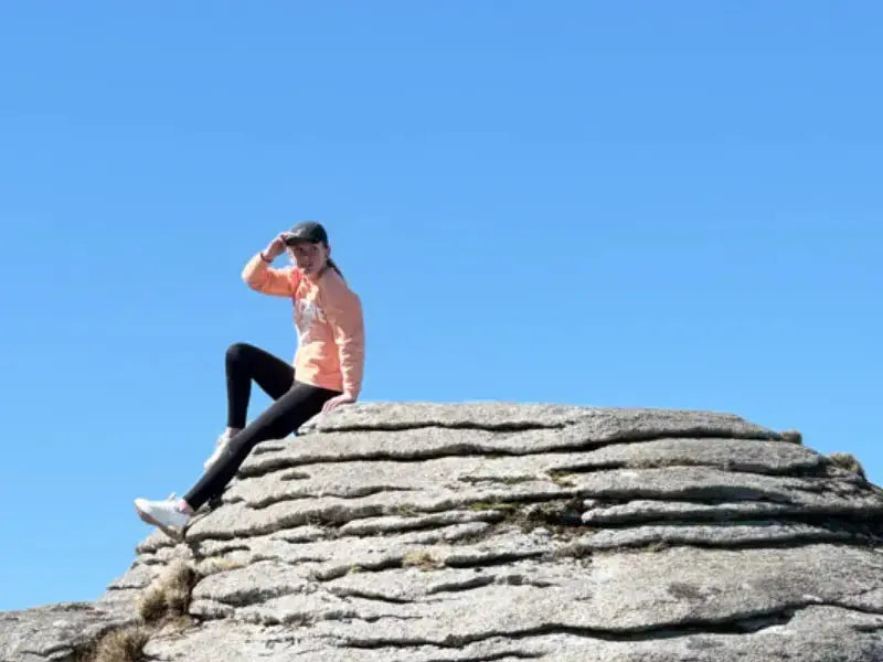 Woman sitting on rock formation illustrating Akiva’s quick easy guide to Victron inverter options