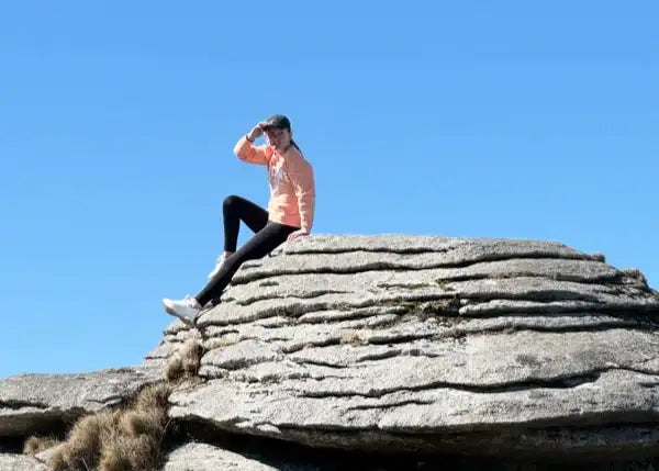 girl with a cap sat on a granite rock